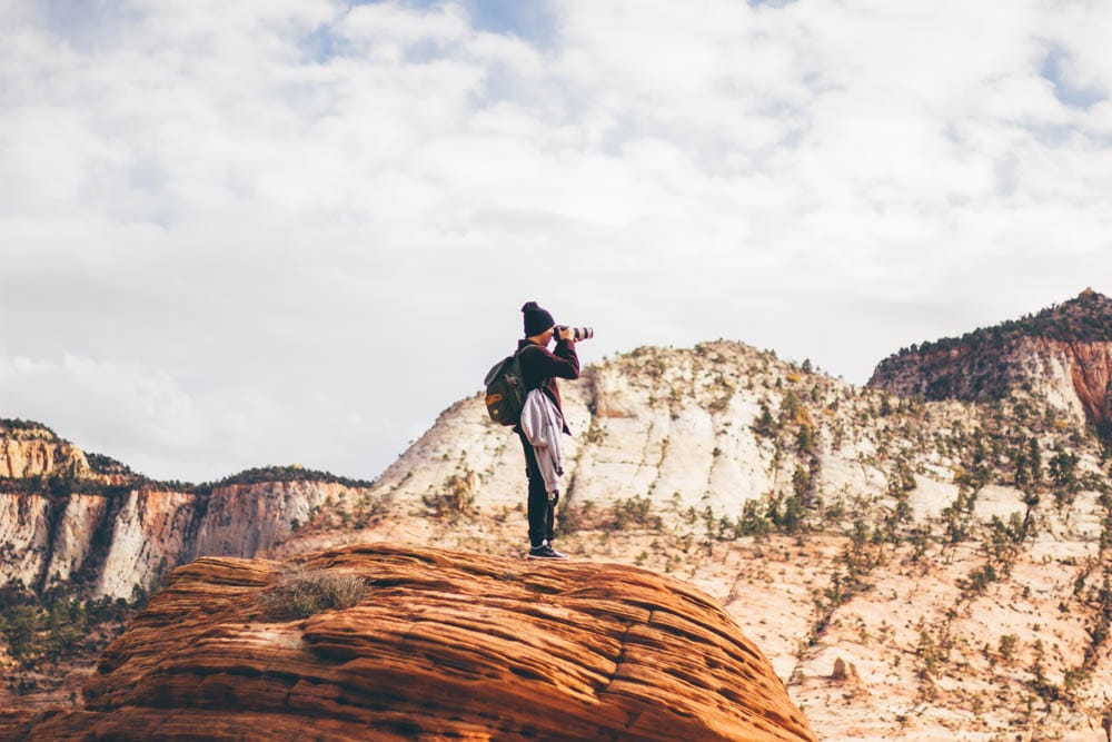 Guy shooting a landscape photo in the middle of a desert canyon