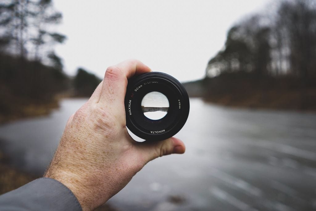 Image of person holding up a lens with the aperture open