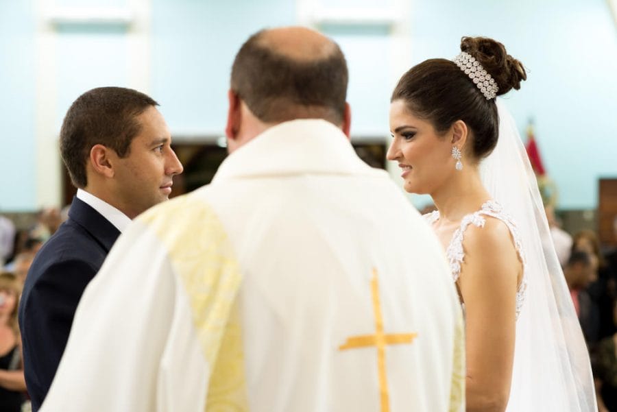 Up-close image of a bride and groom looking at each other in front of their priest while standing at the alter getting married