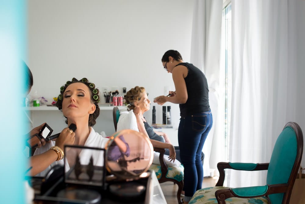 Image of a bride getting her makeup done with her mother also getting hers done in the background to show how to frame bride making of photos in wedding photography