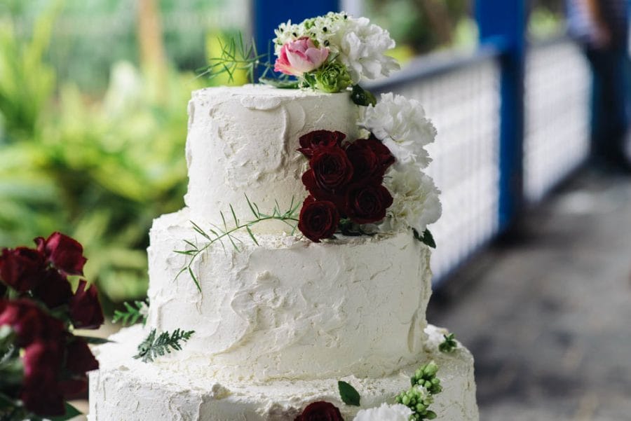 Up close image of a white wedding cake with white, red and pink flowers decorating it
