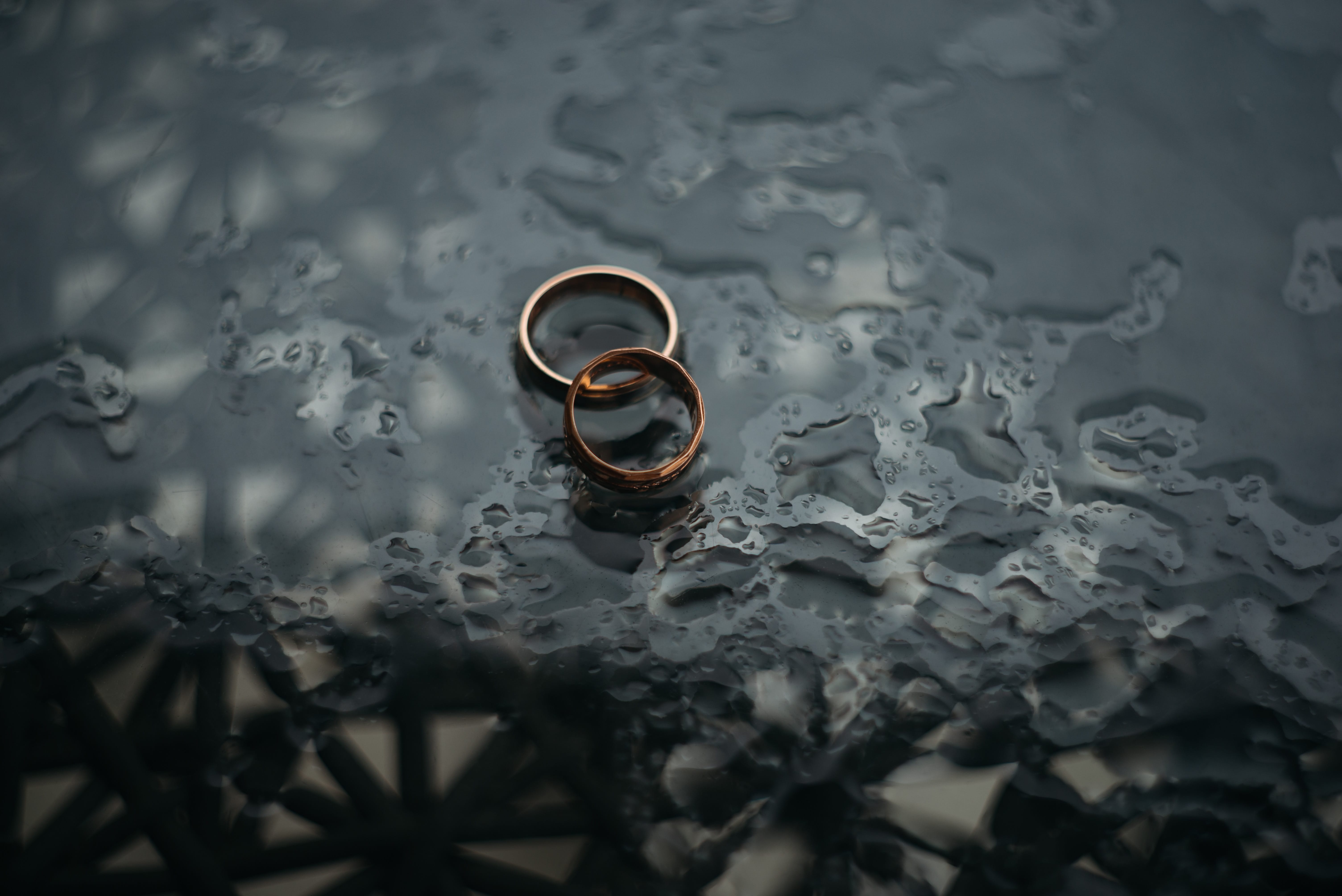Wedding rings on a wet black surface.