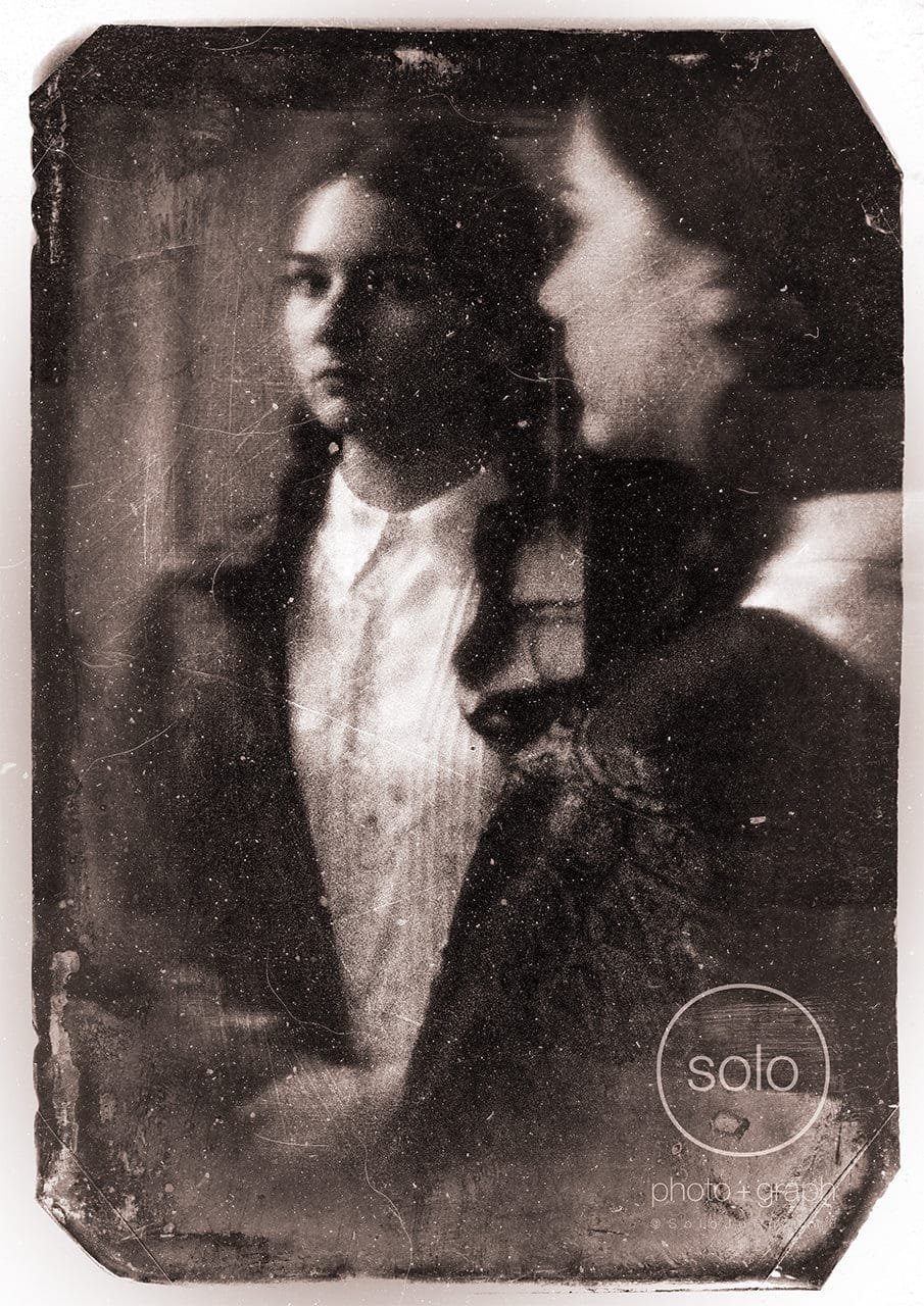 A pinhole portrait of a young woman looking into a mirror.