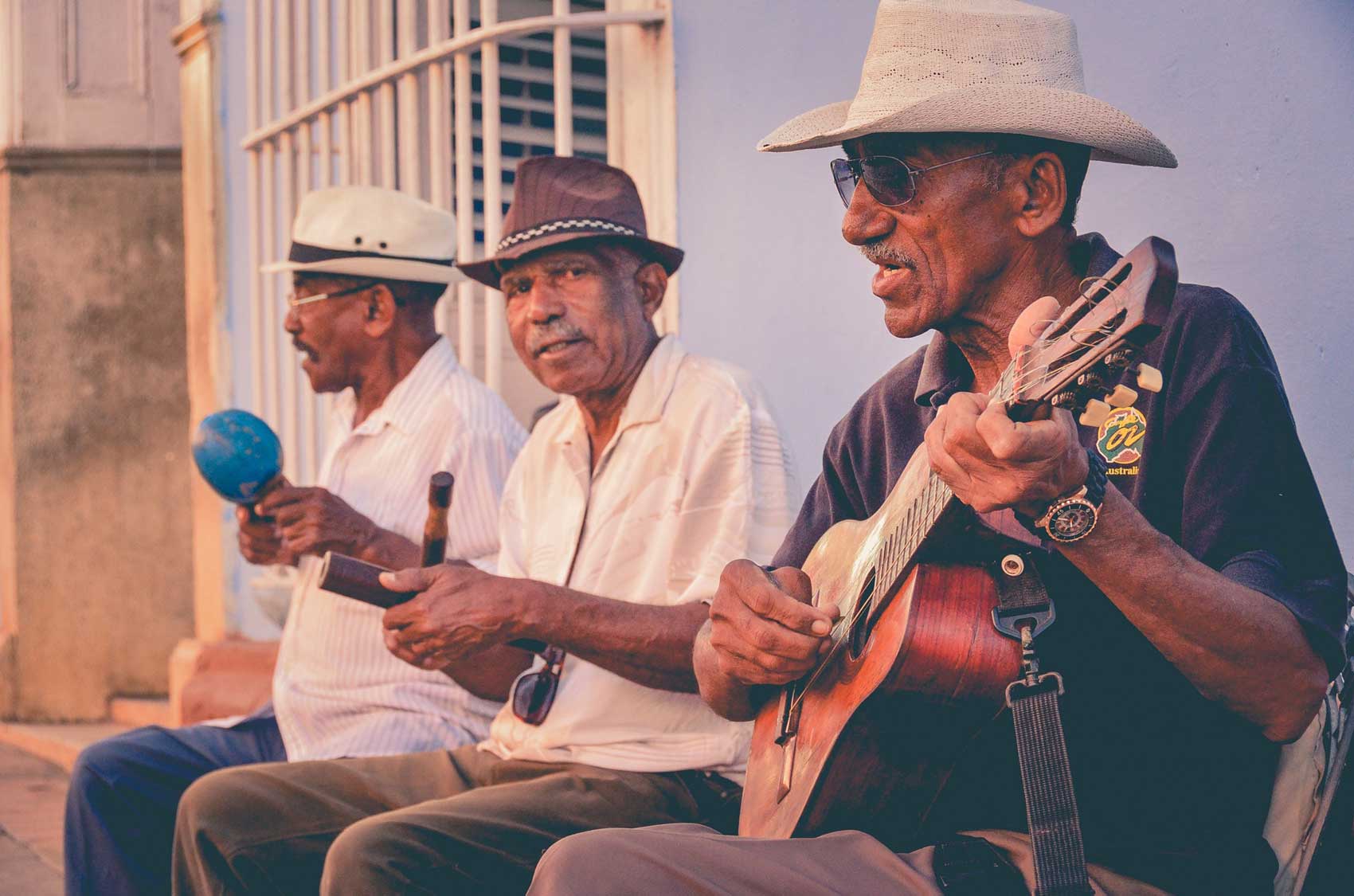 Image of three latino men with hats on playing latin music