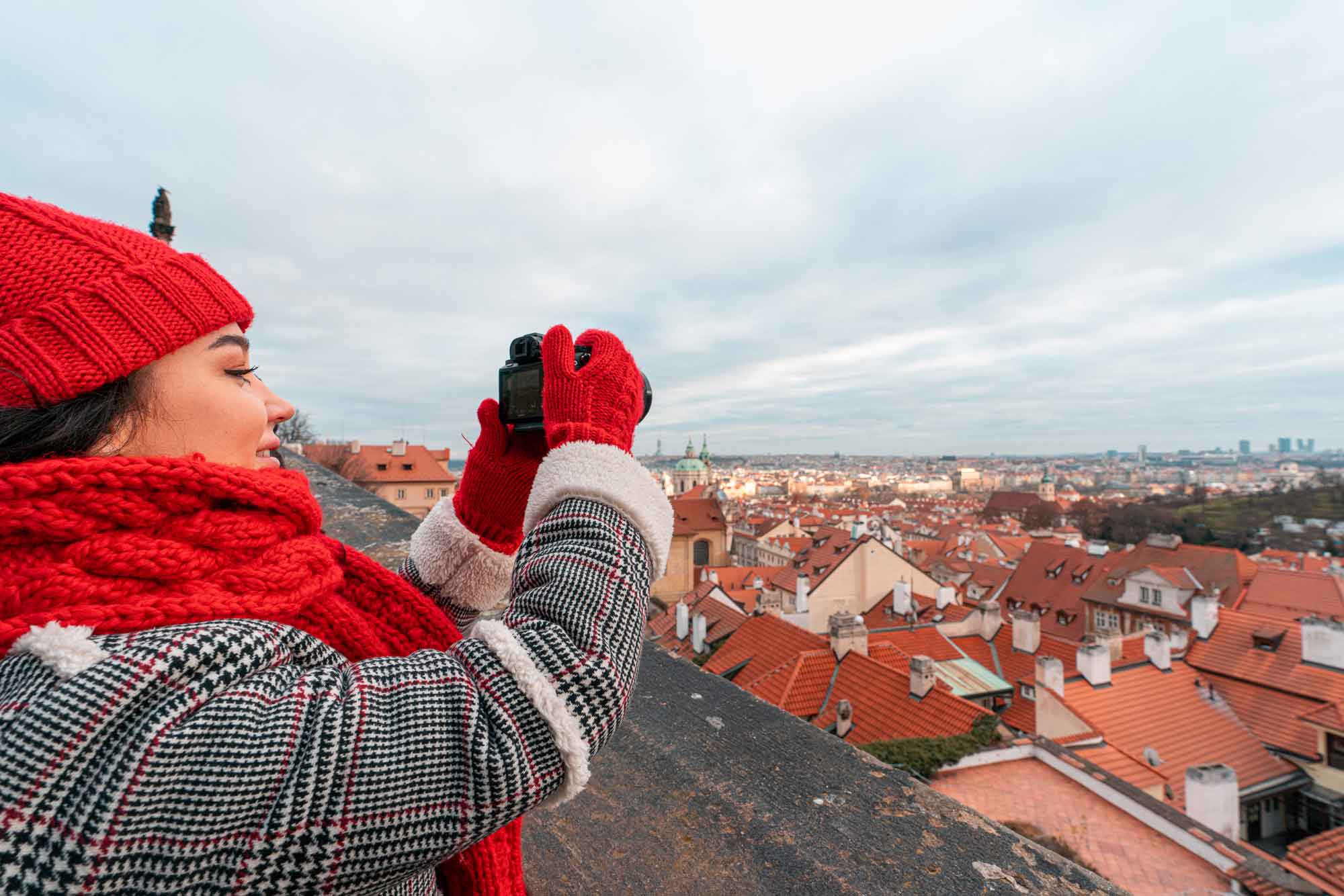 Image of a woman in a red scarf and hat taking Christmas images with a camera on a roof