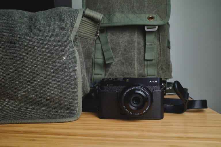 Photo of a simple street photography gear setup with a camera, lens, strap, and camera bags.