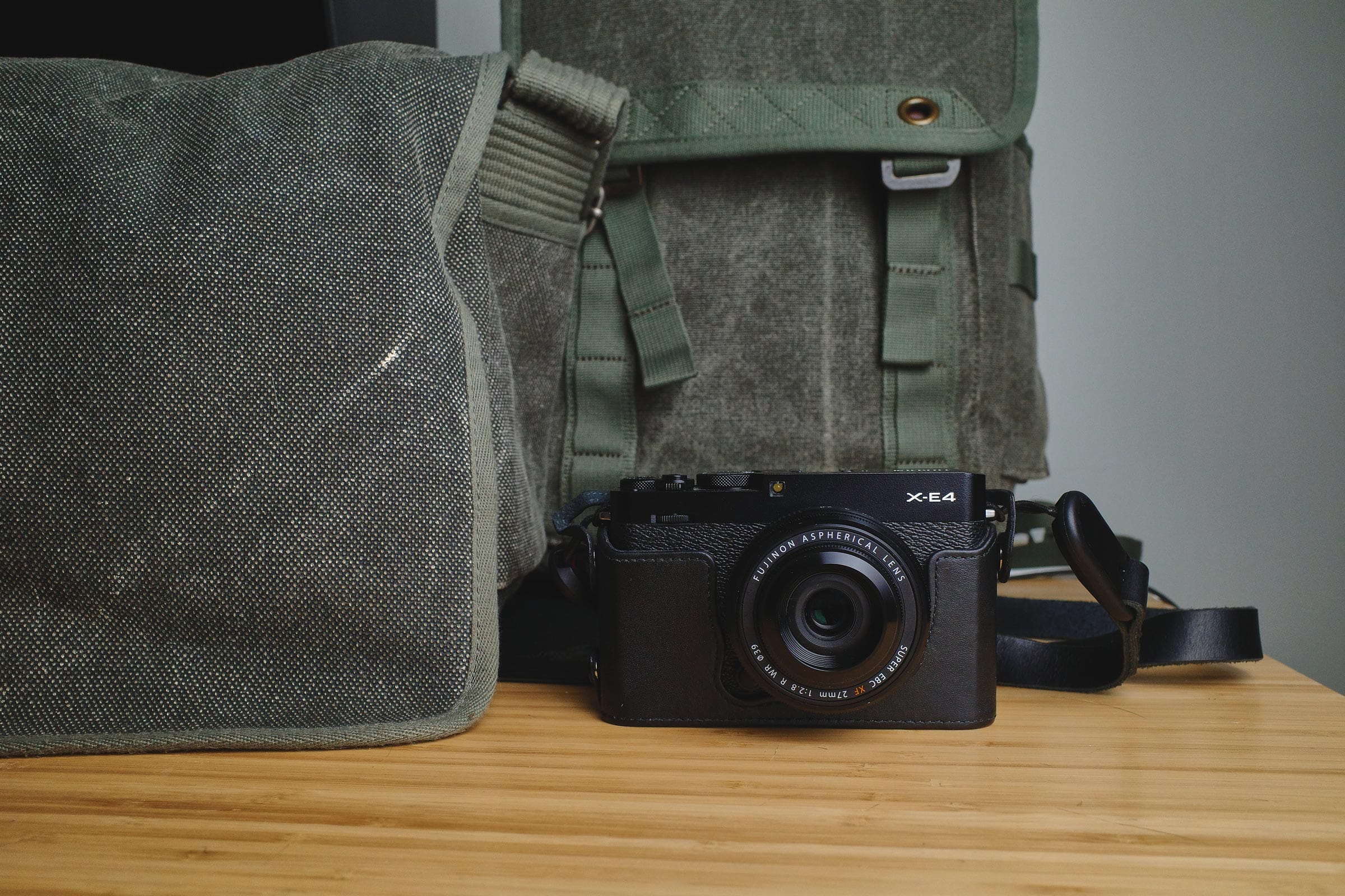 Photo of a simple street photography gear setup with a camera, lens, strap, and camera bags