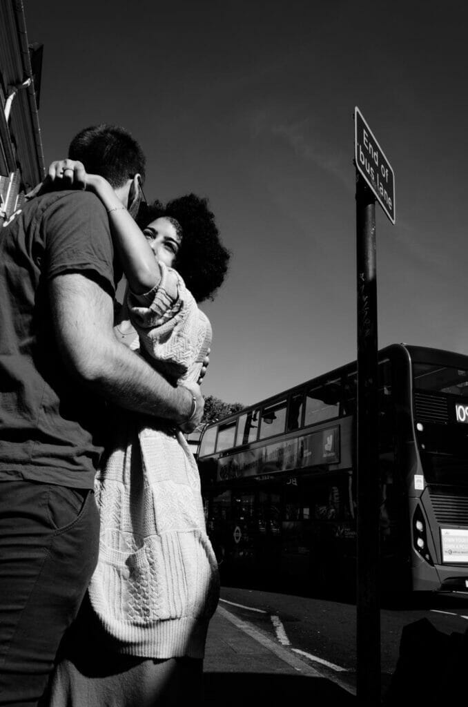 A man and woman hugging each other in front of a bus.