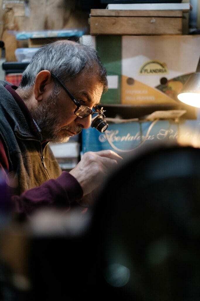 A man doing technical work while wearing glasses with a magnifying glass attached.