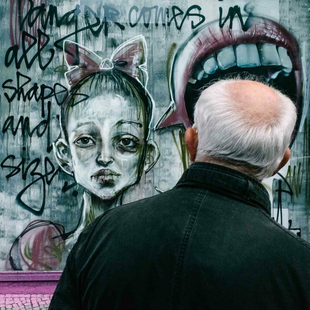 A bald man from behind looking at a wall with grafiti.