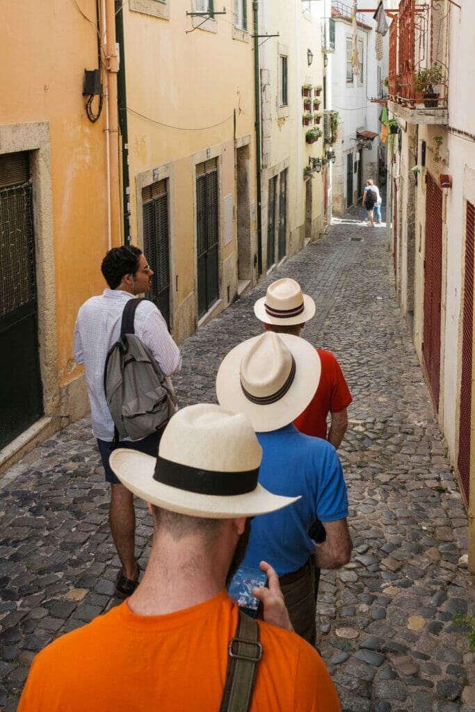 Three men with the same straw hat walking down a narrow alleyway 