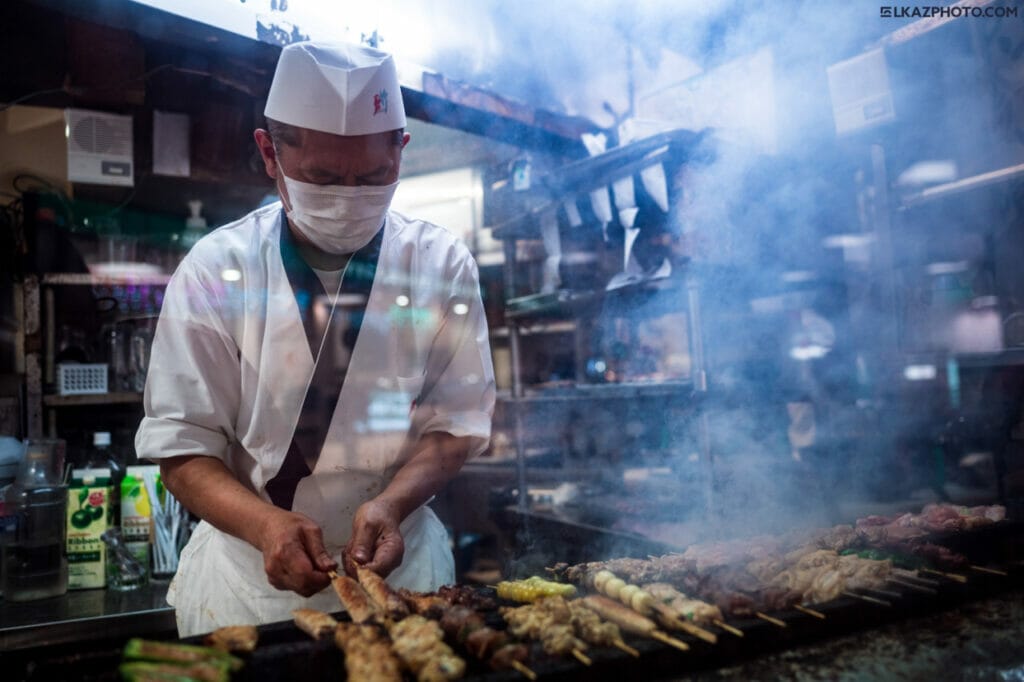A Japanese chef cooking meat skewers.