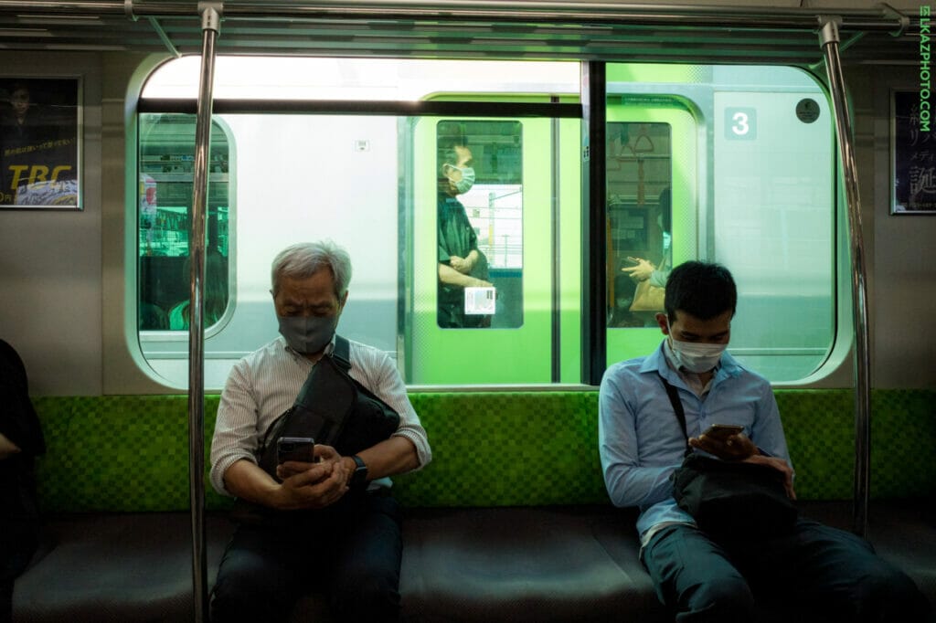 Men looking down at their phones while on a subway or train.