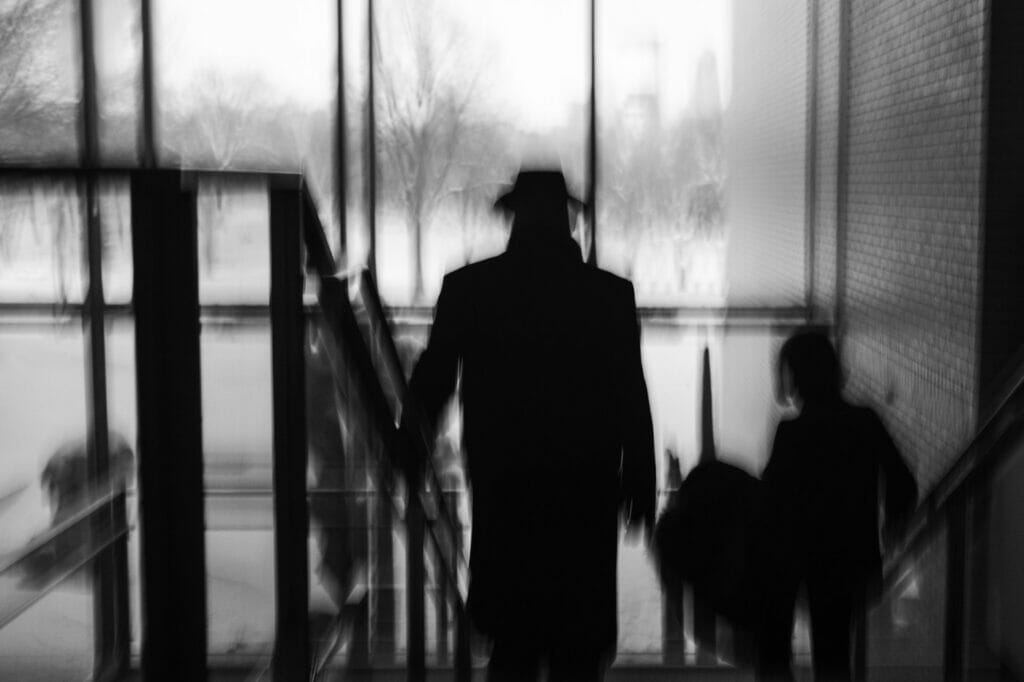 A silhouette of a man wearing a hat going down stairs.
