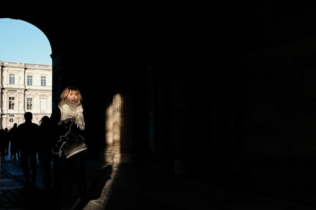 A woman walking in shadow with her face in light.