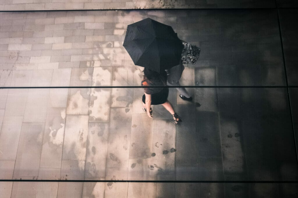 Two women from above walking under an umbrella.